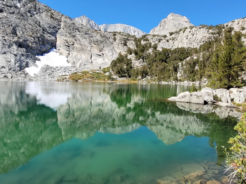 Kristallklarer smaragdgrüner Bergsee im Little Lakes Valley, in dem sich die umliegenden Granitberge spiegeln.